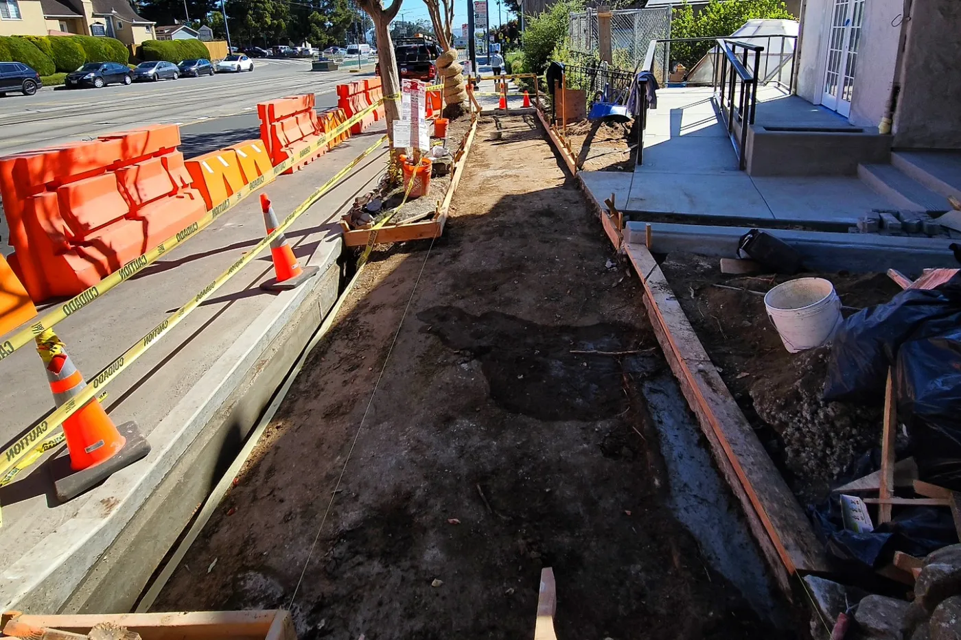 Excavated sidewalk strip with barriers and cones along the street — ADA Ramp & Sidewalk — West Portal, West Portal, San Francisco