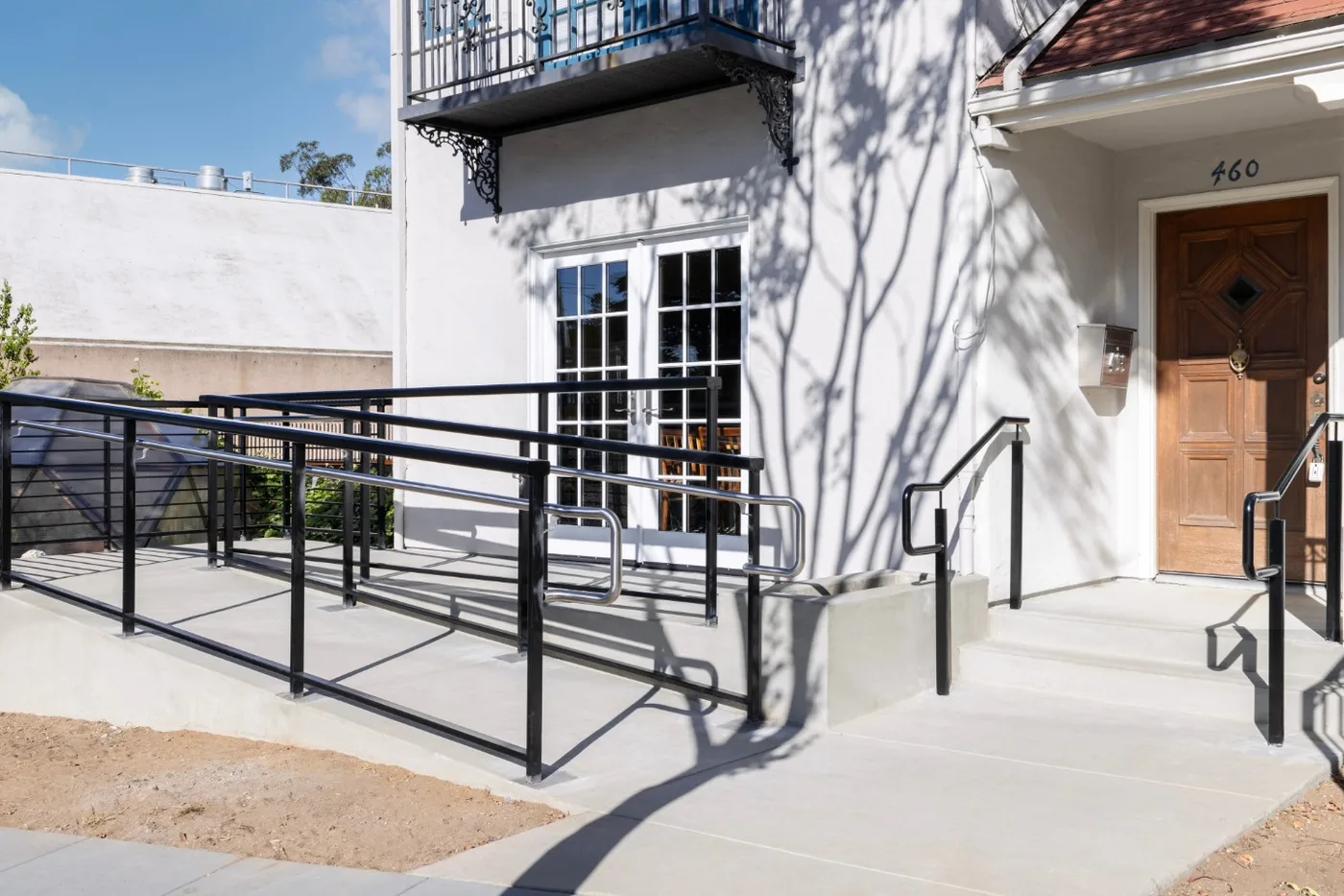 Completed ADA ramp with steel handrails at the building entry — West Portal, San Francisco