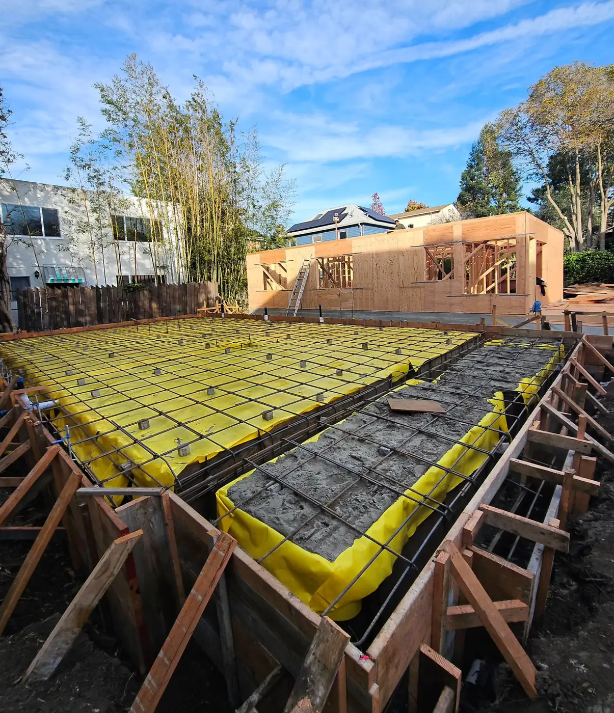 Formwork rebar + foam, framed ADU behind — ADU Foundations — Two Projects, SF Bay Area