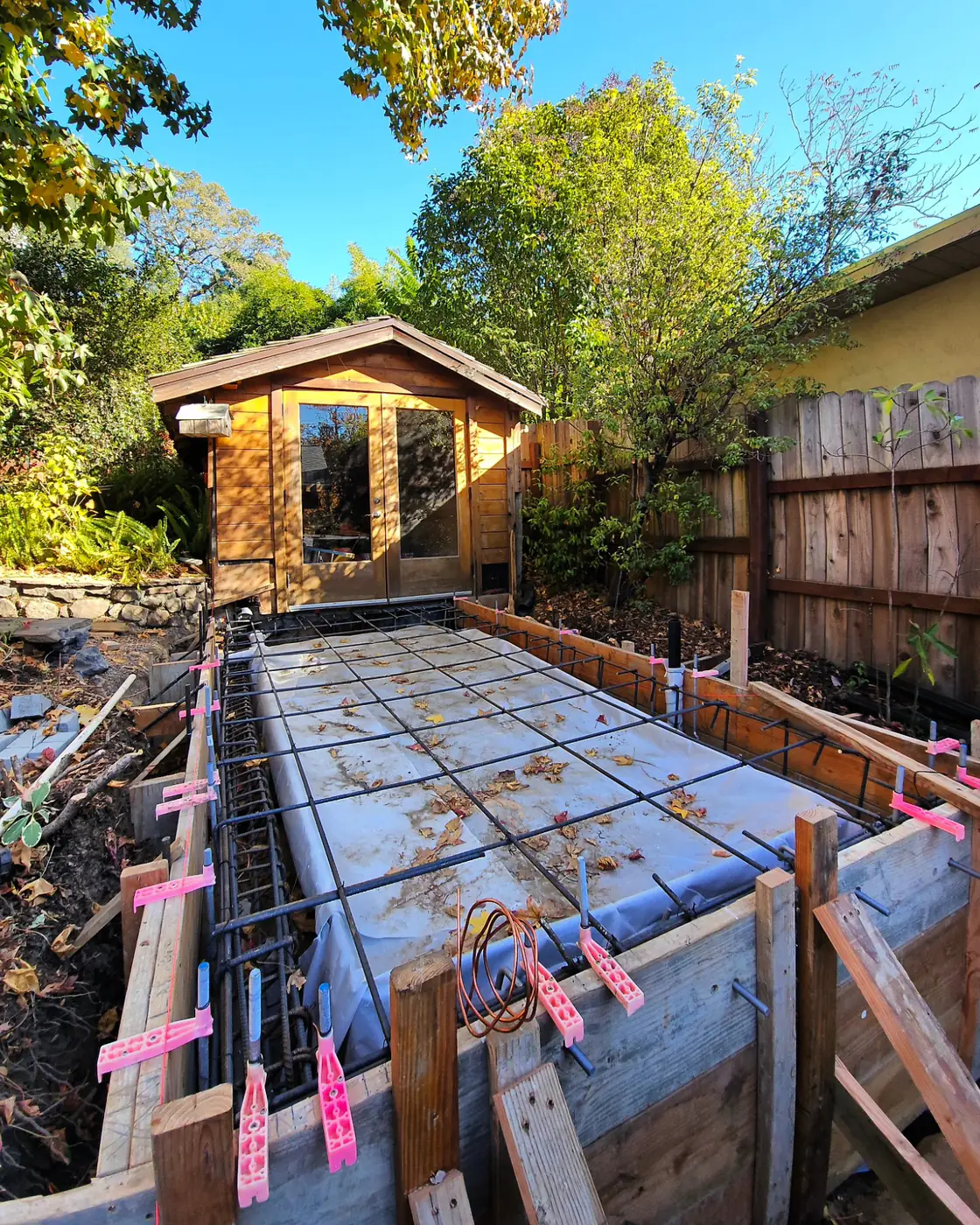 Rebar in wood forms, cedar ADU behind — Backyard ADU Foundation, San Rafael, CA