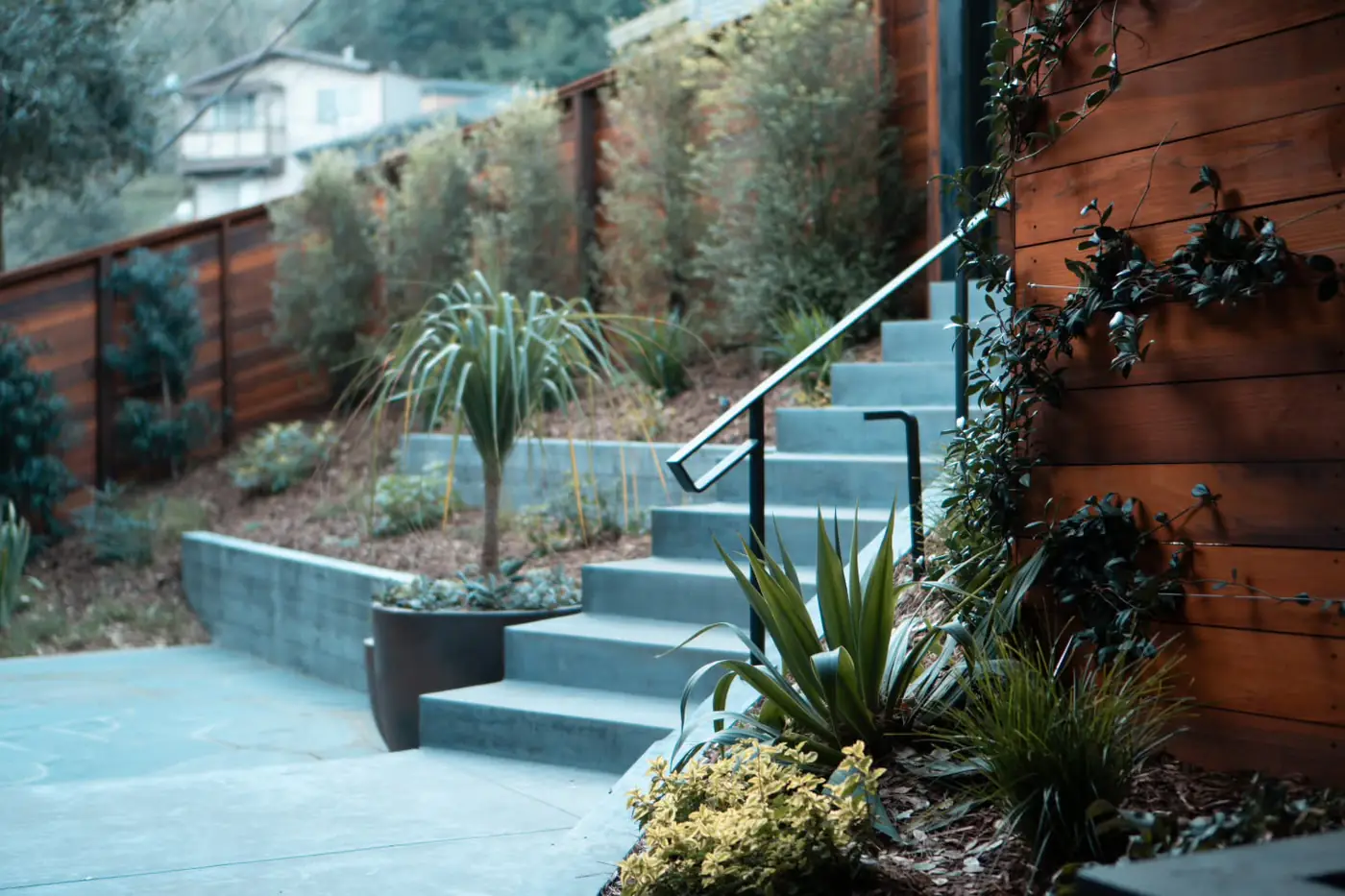 Finished concrete stairs with a steel handrail on a Bay Area hillside home, lit at dusk