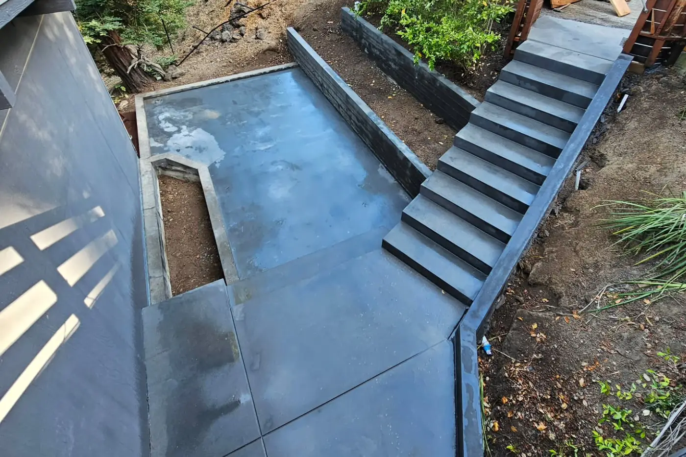 Aerial finished dark concrete patio + wide stairs — Hillside Outdoor Living Transformation, Oakland, CA