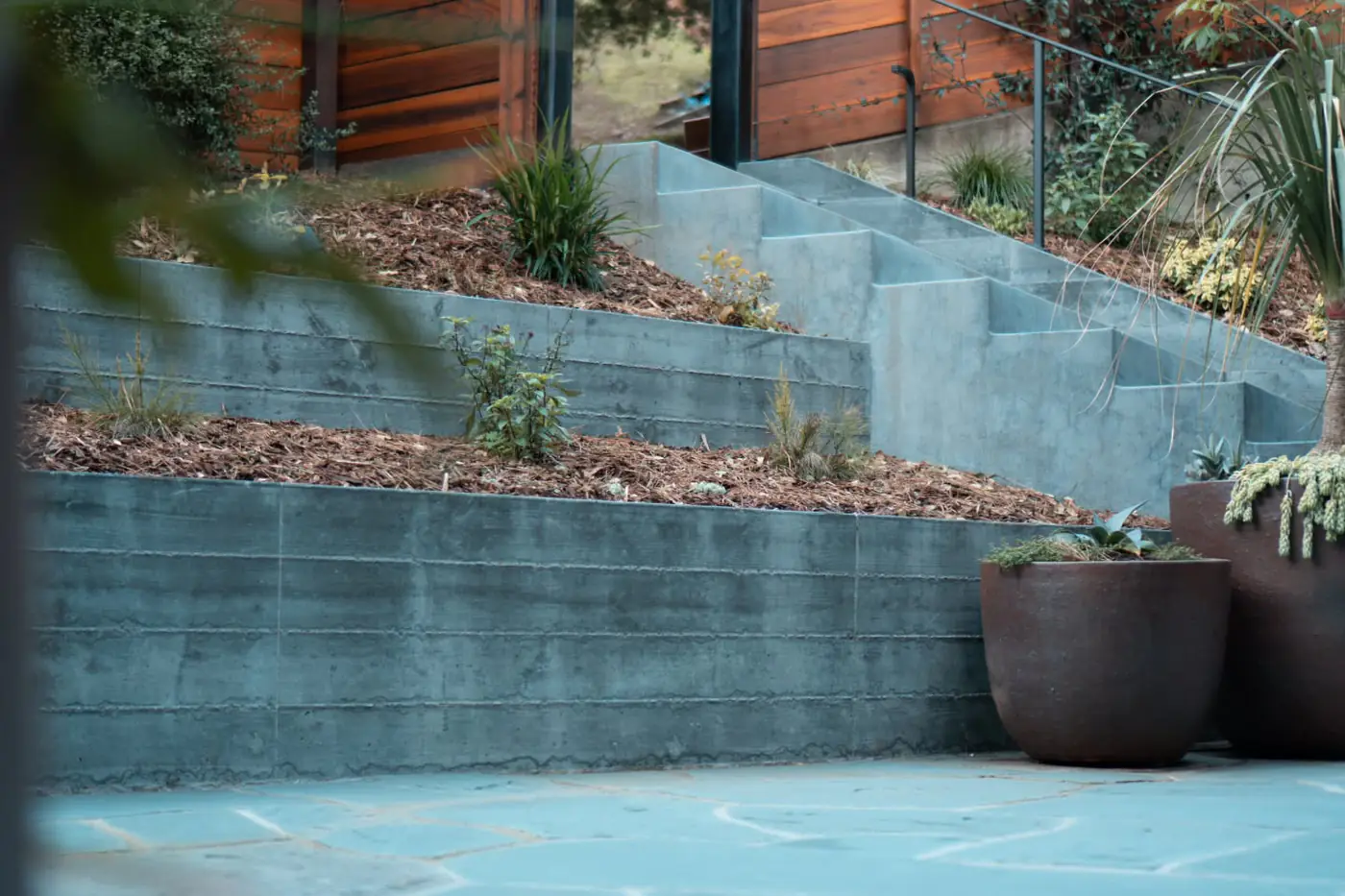 A two-tier concrete retaining wall with terraced planters in a finished Oakland backyard, built by New Edge Concrete