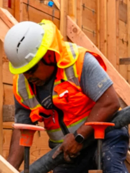 Roberto Santana, co-founder of New Edge Concrete, guiding a concrete pump hose into formwork