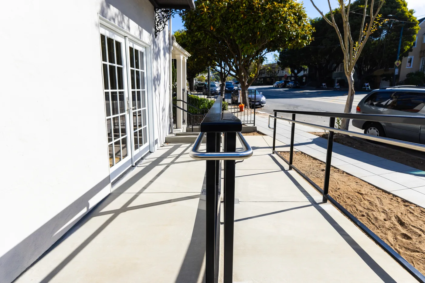 Along the finished walkway between the French doors and the ramp railing, street beyond — ADA Ramp & Sidewalk — West Portal, West Portal, San Francisco