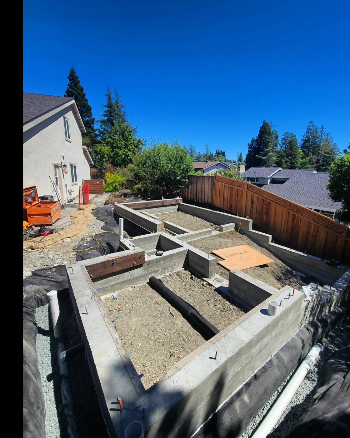 The completed stem-wall foundation stepping down the hillside, waterproofing on the downhill walls — Danville ADU Foundation, Danville, CA