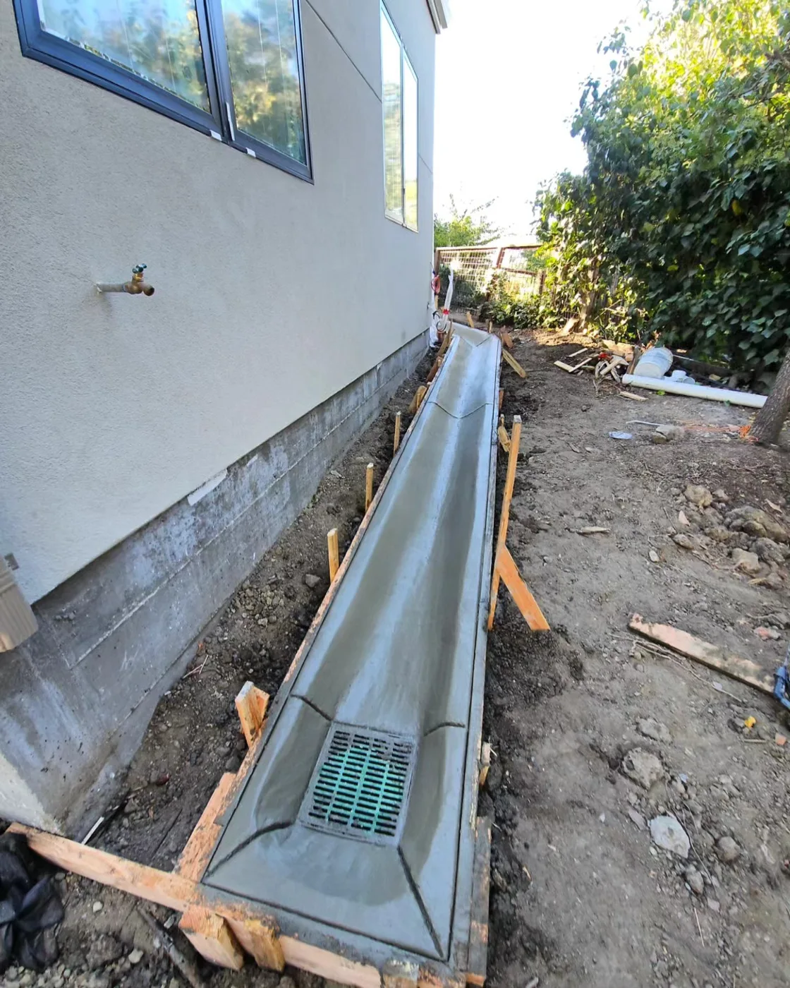 The finished curb-and-channel with its cast-in drain grate along the home’s foundation — Danville Landing Pad & Curb Drainage, Danville, CA