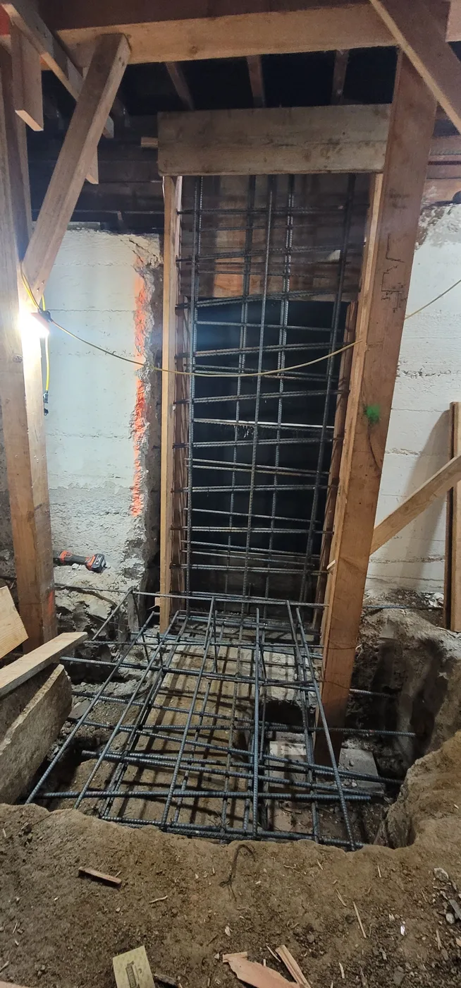 Wall rebar between shoring posts with footing reinforcement below — Durant Basement Foundation, Berkeley, CA