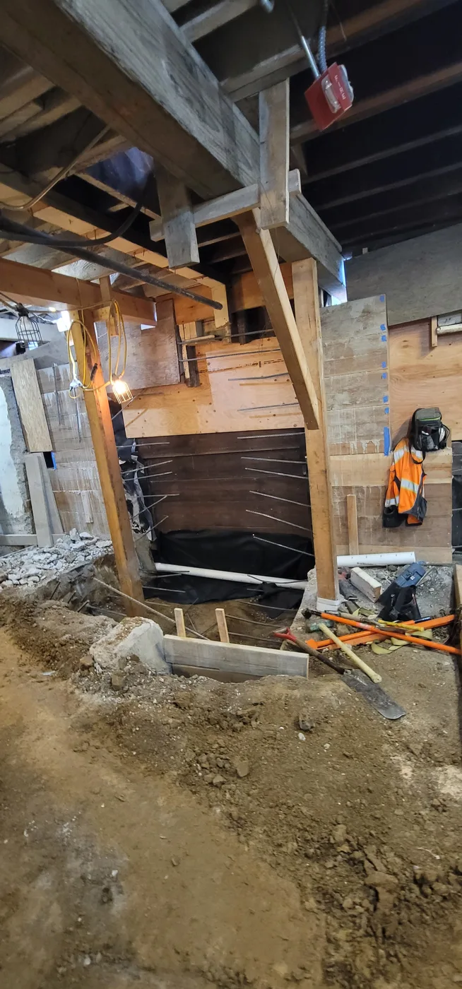 Hand excavation around temporary shoring posts deep in the basement — Durant Basement Foundation, Berkeley, CA