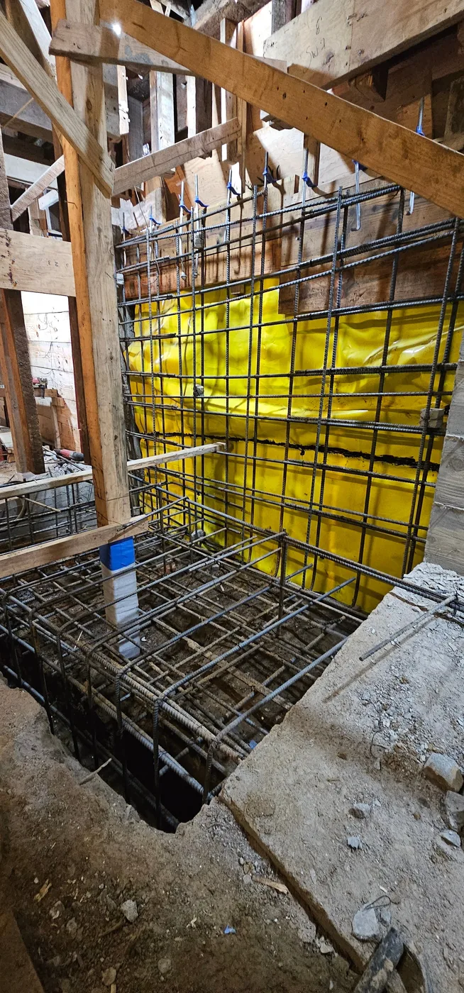 Dense rebar cages at a grade-beam corner with waterproofing behind — Durant Basement Foundation, Berkeley, CA
