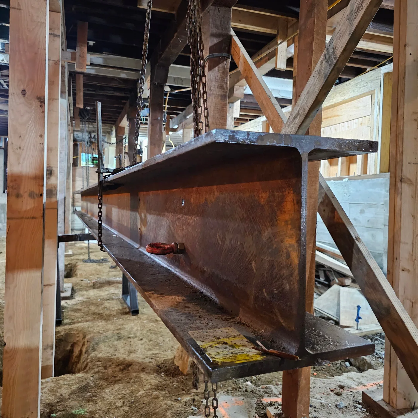 Steel beam hung on chains, ready to be set for the seismic upgrade — Durant Basement Foundation, Berkeley, CA