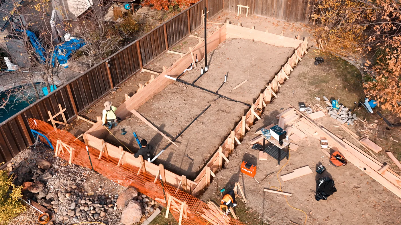 Crew working the formed footprint with underslab plumbing run across the graded pad — Moraga Backyard ADU, Moraga, CA
