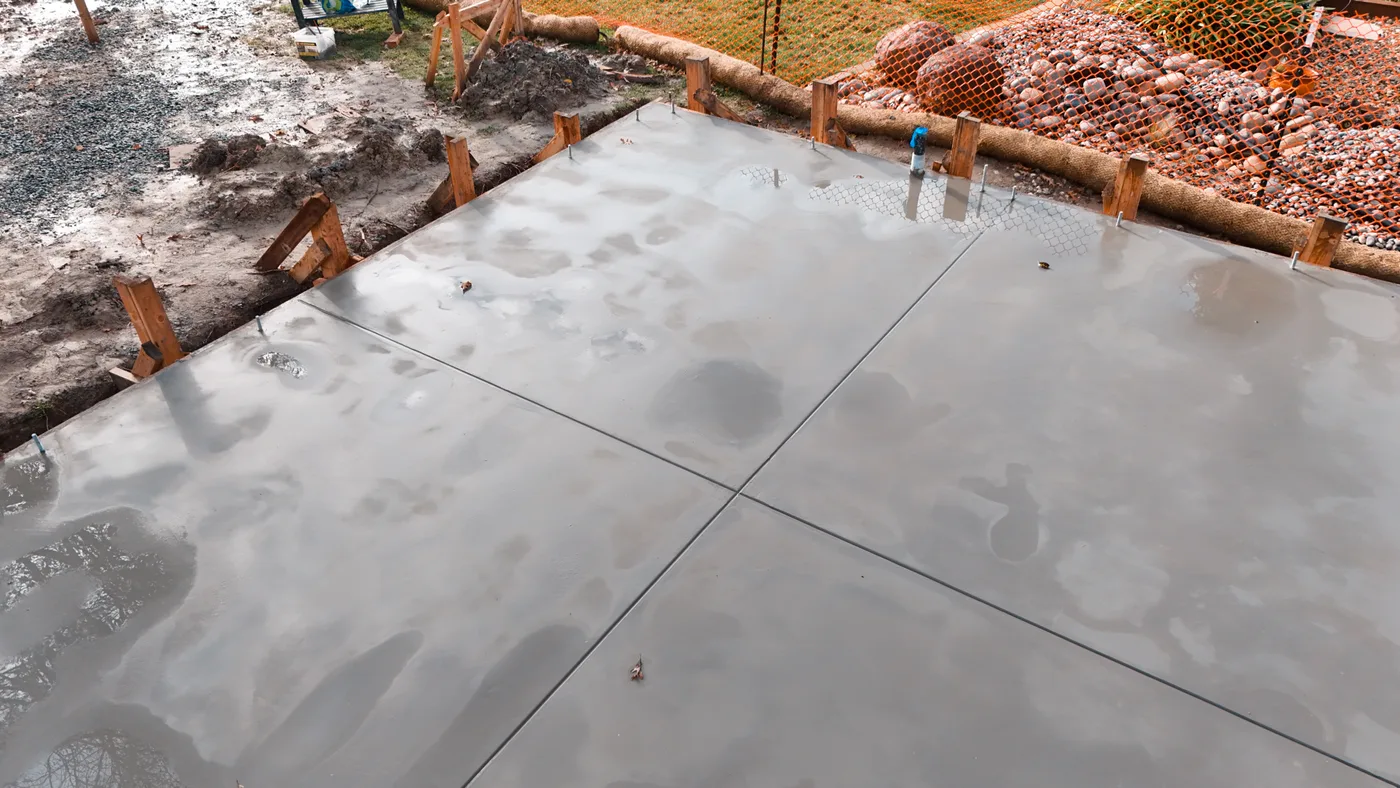 Close view across the smooth-troweled surface with tooled joints and anchor bolts along the edge — Moraga Backyard ADU, Moraga, CA