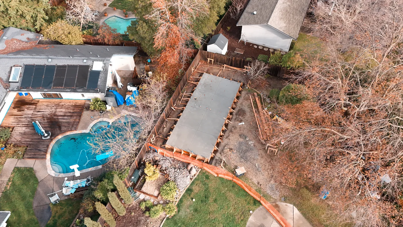 High aerial of the slab at the back of the lot, erosion-control fencing running through the yard — Moraga Backyard ADU, Moraga, CA