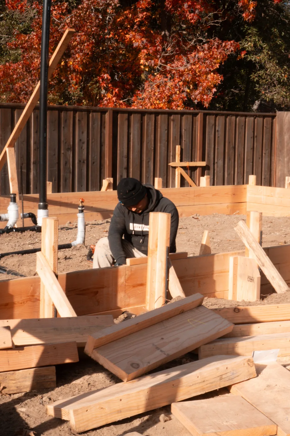 Formsetter working the perimeter boards, plumbing stub-outs rising through the pad — Moraga Backyard ADU, Moraga, CA