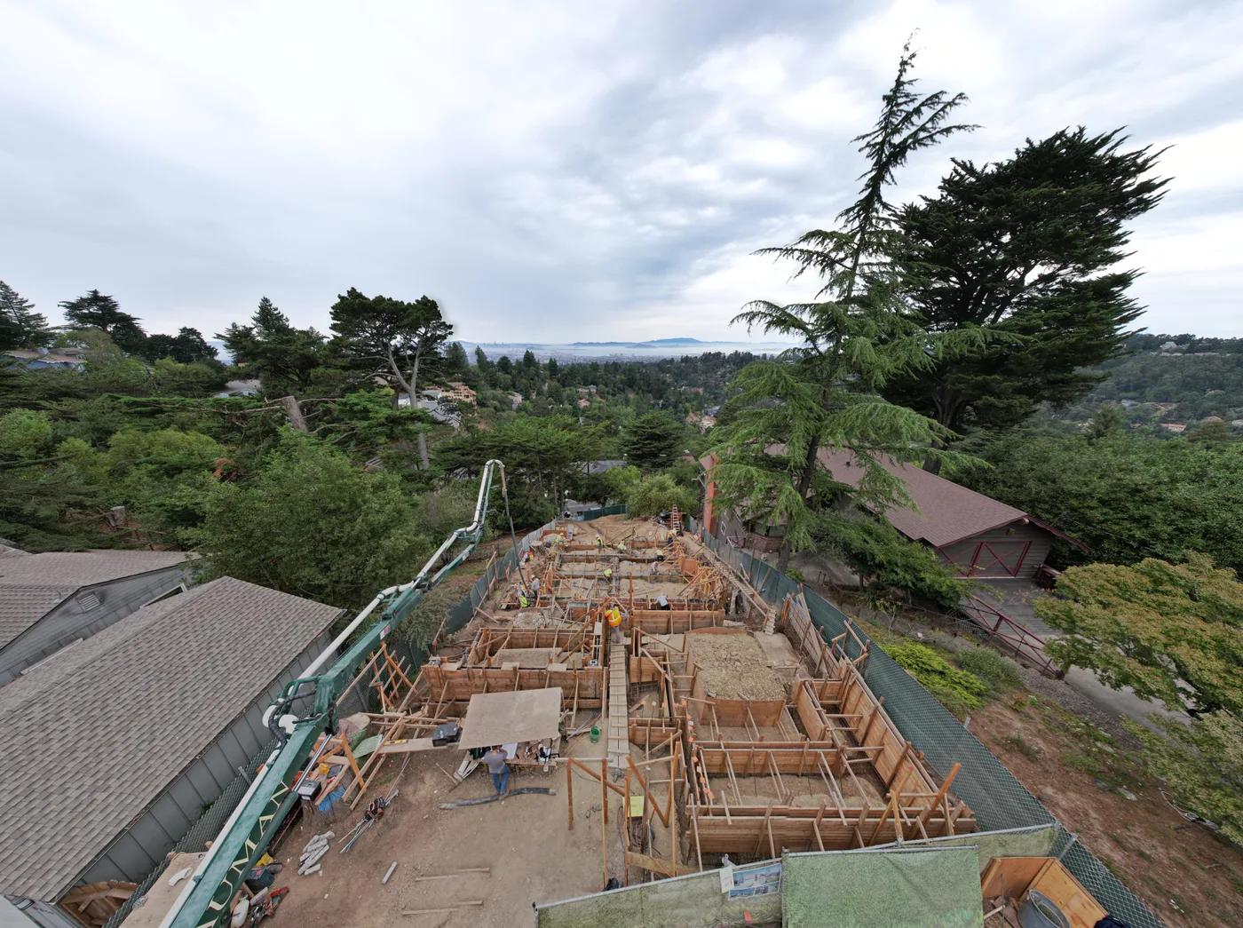 Formed foundation and retaining walls stepping down an Oakland Hills site toward the bay — a custom home foundation by New Edge Concrete