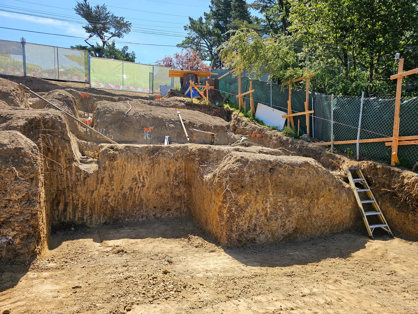 Deep hillside excavation with benched soil walls and an access ladder — Oakland Hills Custom Home, Oakland, CA