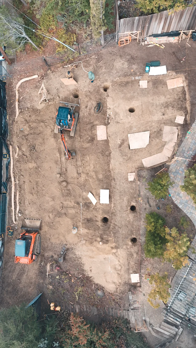 Aerial down the length of the excavated pad with footing trenches cut and piers drilled — Steep Hillside Lafayette ADU, Lafayette, CA