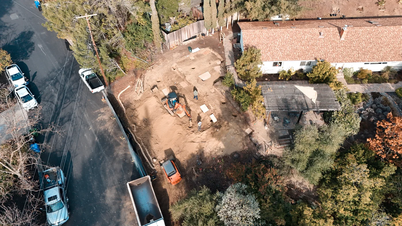 Aerial of the hillside lot from the street with excavation underway between the road and the existing house — Steep Hillside Lafayette ADU, Lafayette, CA