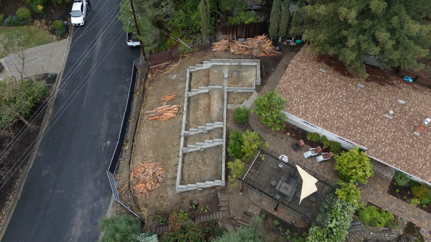 Aerial of the finished foundation alongside the street, erosion control still running the frontage — Steep Hillside Lafayette ADU, Lafayette, CA